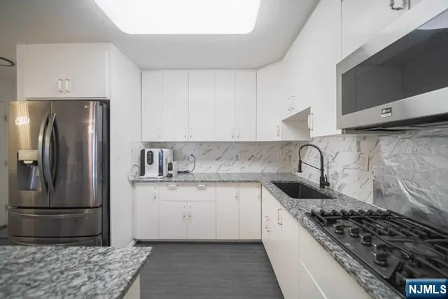 a kitchen with stainless steel appliances granite countertop a sink stove and refrigerator