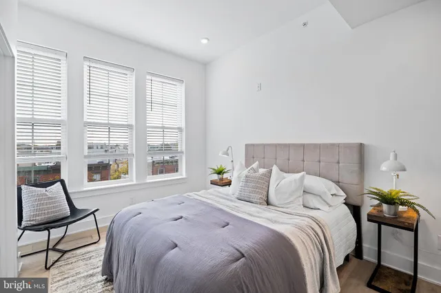 a bedroom with a bed a chair and next to a window