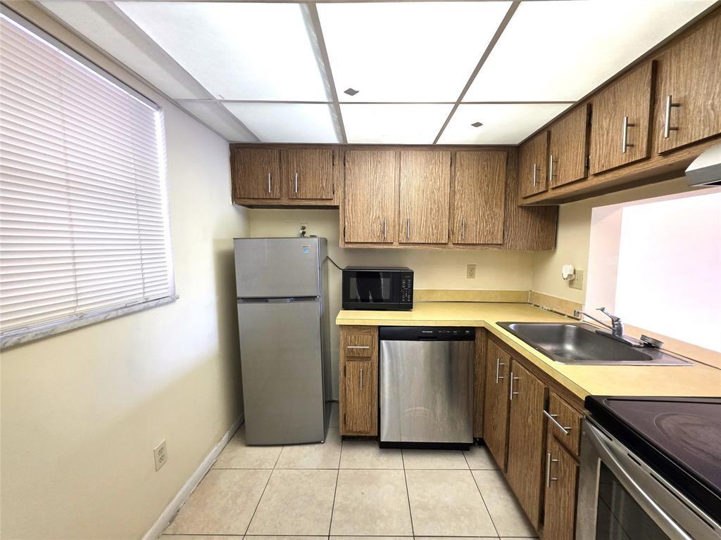 2800 Northwest 56th Avenue, Unit E304 Lauderhill, FL 33313 - Photo 5 of 15 a kitchen with stainless steel appliances granite countertop a sink a stove a refrigerator a washer dryer and white cabinets