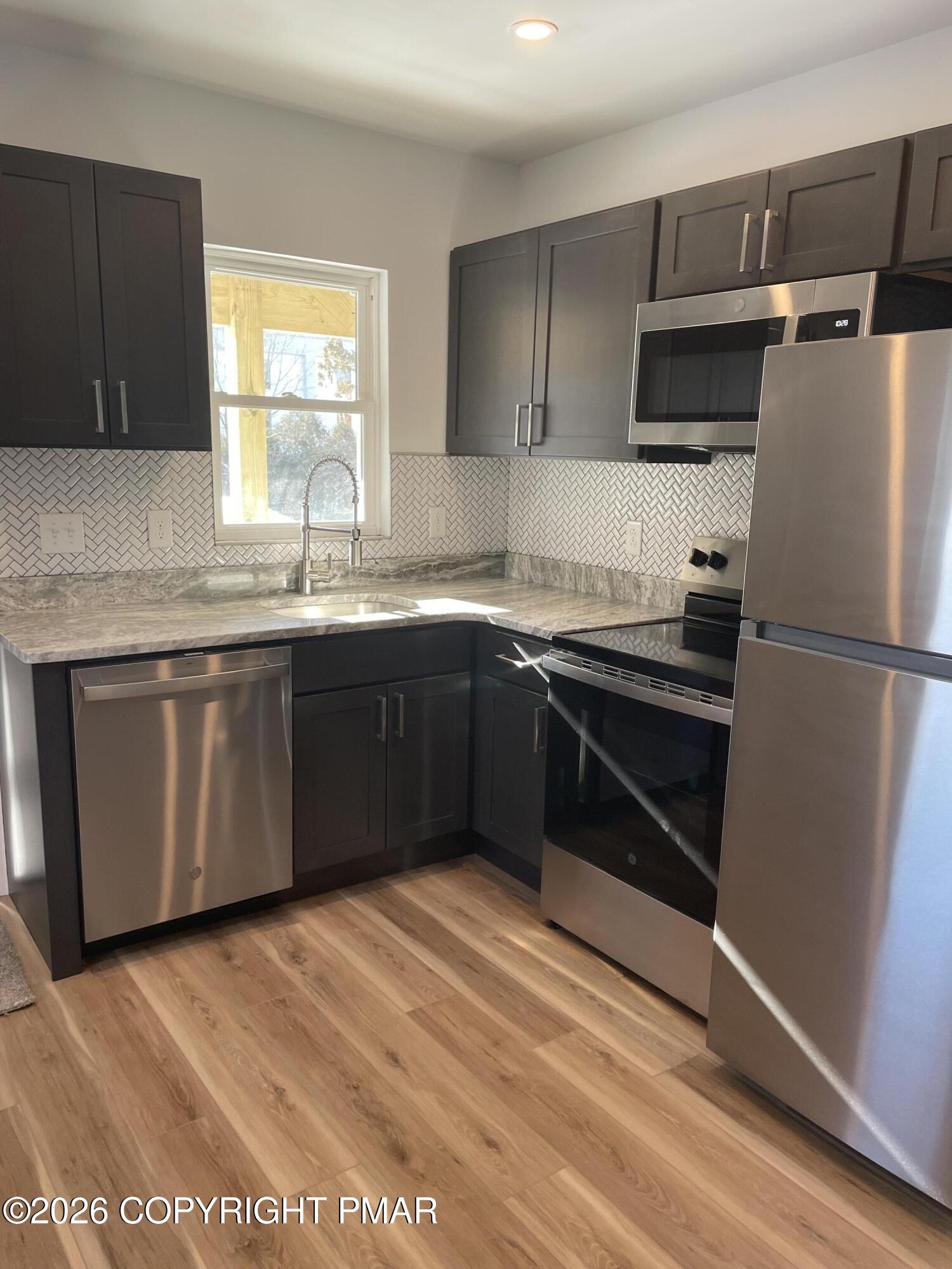 733 Ann Street, Unit 2 Stroudsburg, PA 18360 - Photo 3 of 16 a kitchen with stainless steel appliances granite countertop a sink stove and refrigerator