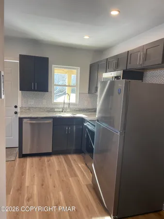 a kitchen with stainless steel appliances granite countertop a refrigerator a sink a stove top oven a counter space and cabinets