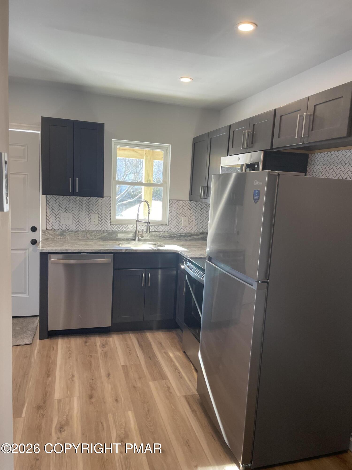 733 Ann Street, Unit 2 Stroudsburg, PA 18360 - Photo 6 of 16 a kitchen with stainless steel appliances granite countertop a refrigerator a sink a stove top oven a counter space and cabinets
