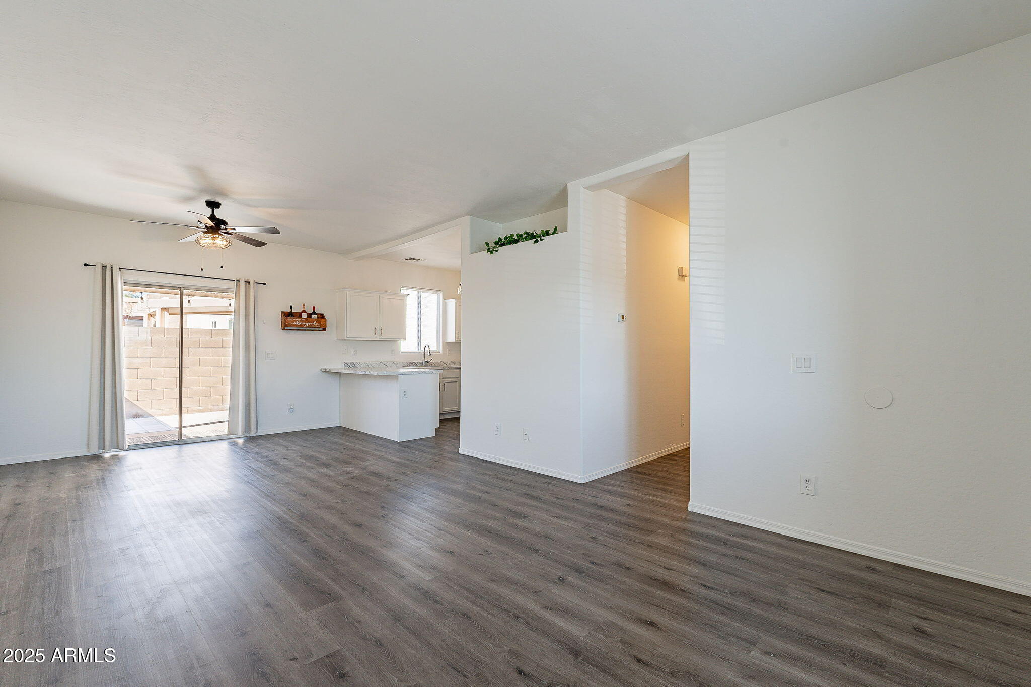 2300 East Magma Road, Unit 160 San Tan Valley, AZ 85143 - Photo 4 of 44 a view of a kitchen and an empty room with wooden floor and a window
