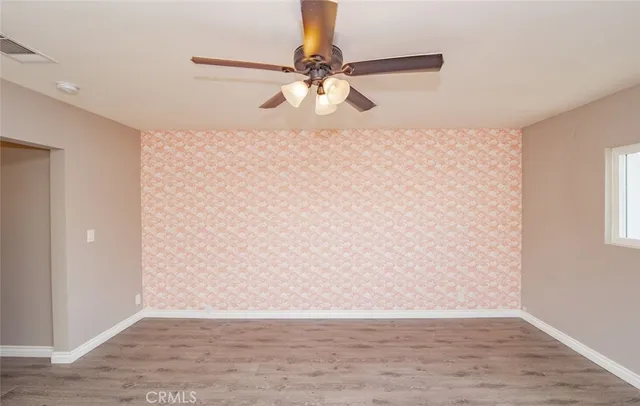 a view of a room with wooden floor a ceiling fan and a window