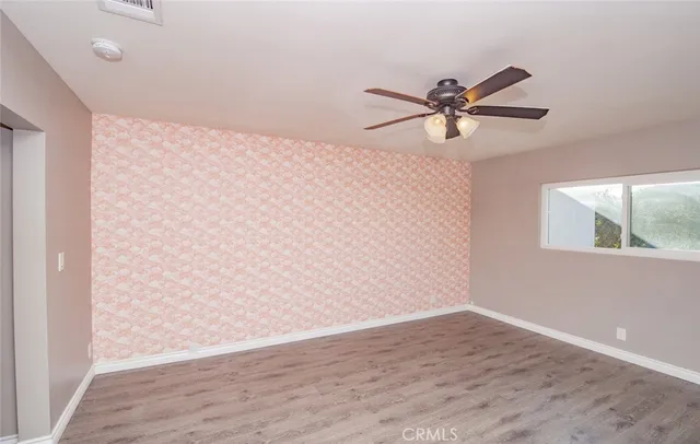 a view of a big room with wooden floor and a chandelier fan