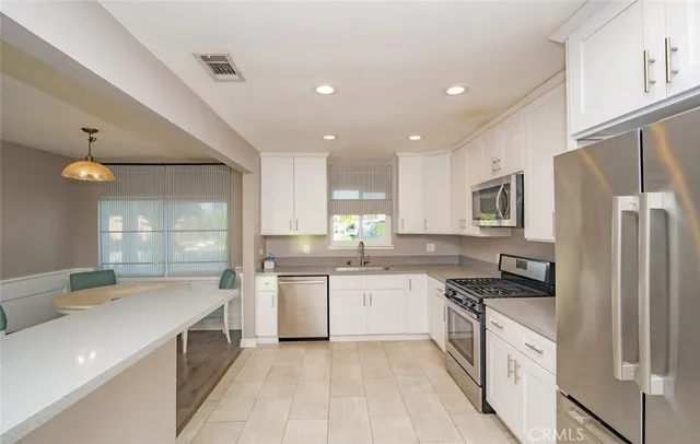 a large kitchen with stainless steel appliances lots of white cabinets