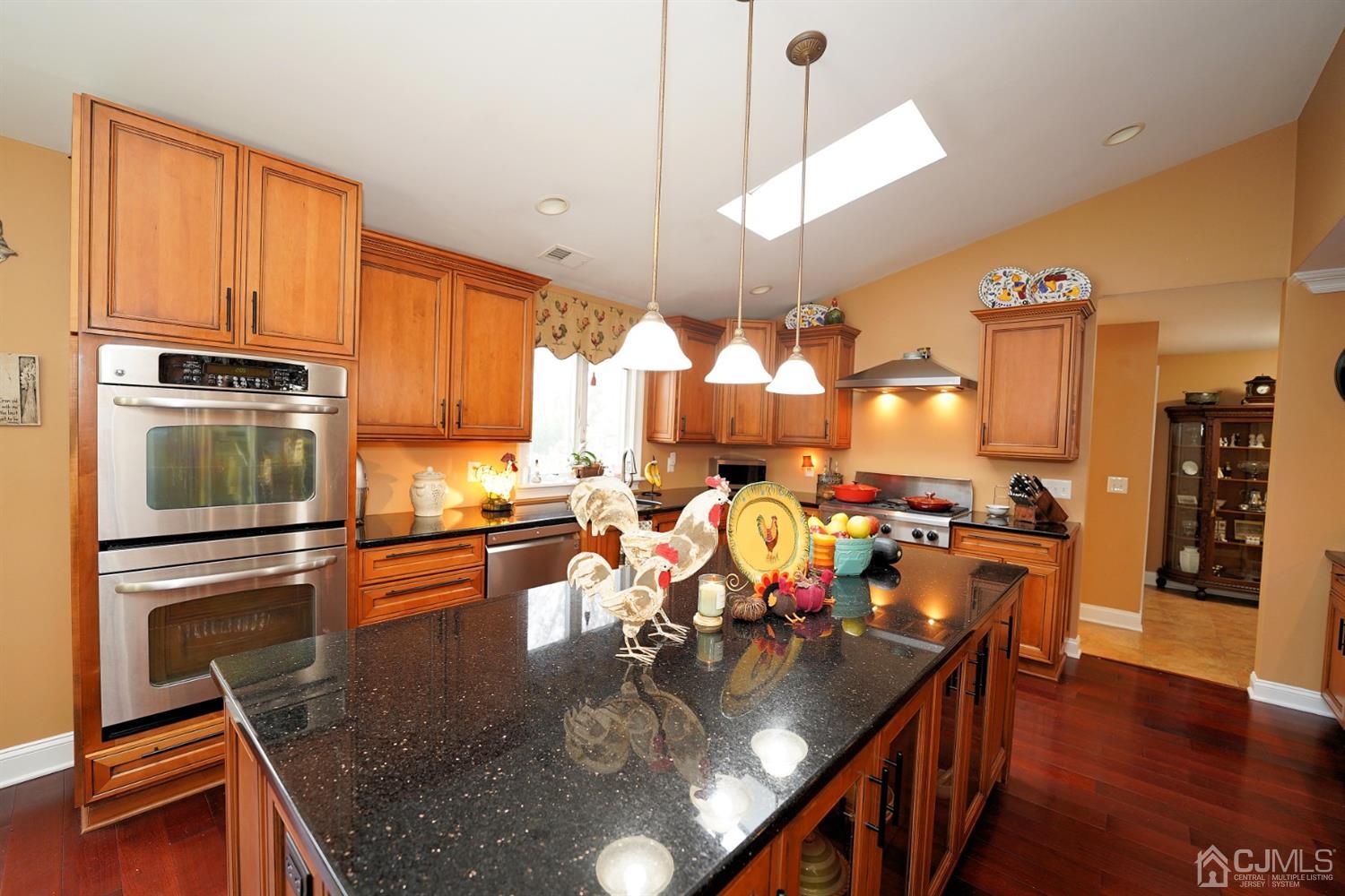 56 Kingsley Road Kendall Park, NJ 08824 - Photo 20 of 62 a kitchen with stainless steel appliances granite countertop a stove top oven a dining table and chairs with wooden floor