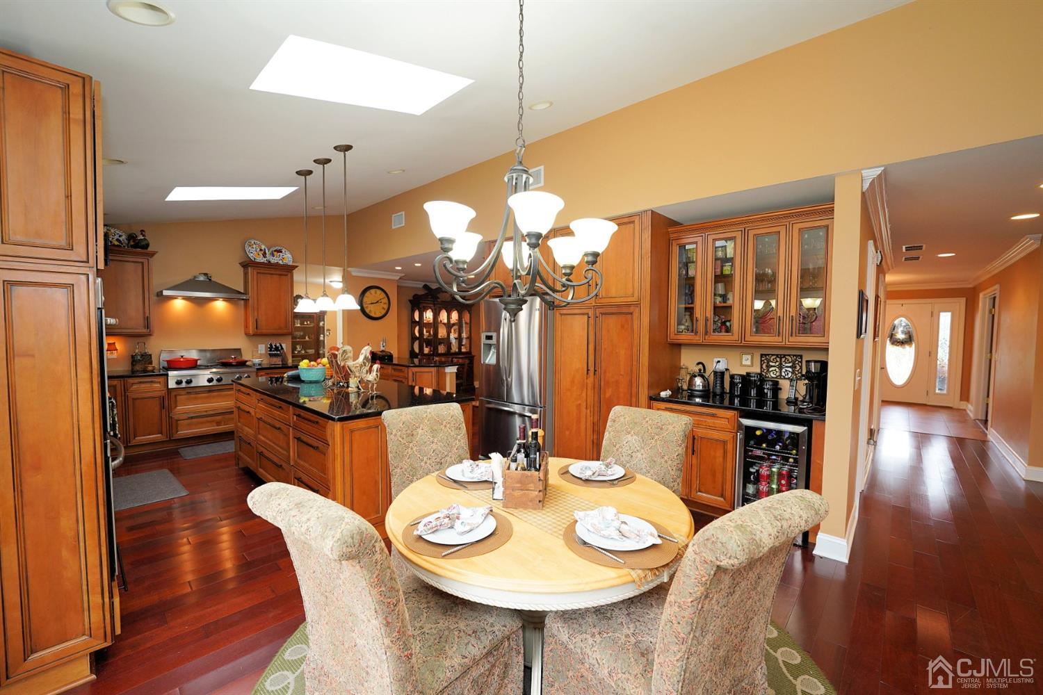 56 Kingsley Road Kendall Park, NJ 08824 - Photo 24 of 62 a dining room with wooden floor a chandelier a wooden table and chairs