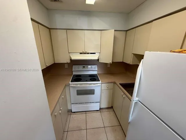 a kitchen with a sink a refrigerator and cabinets