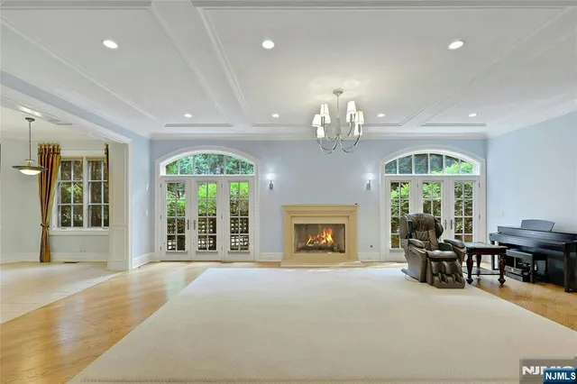 a view of a livingroom with furniture chandelier fireplace and large windows
