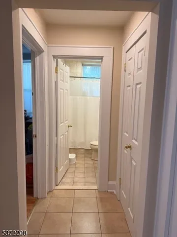 a view of a hallway with wooden floor and a bathroom