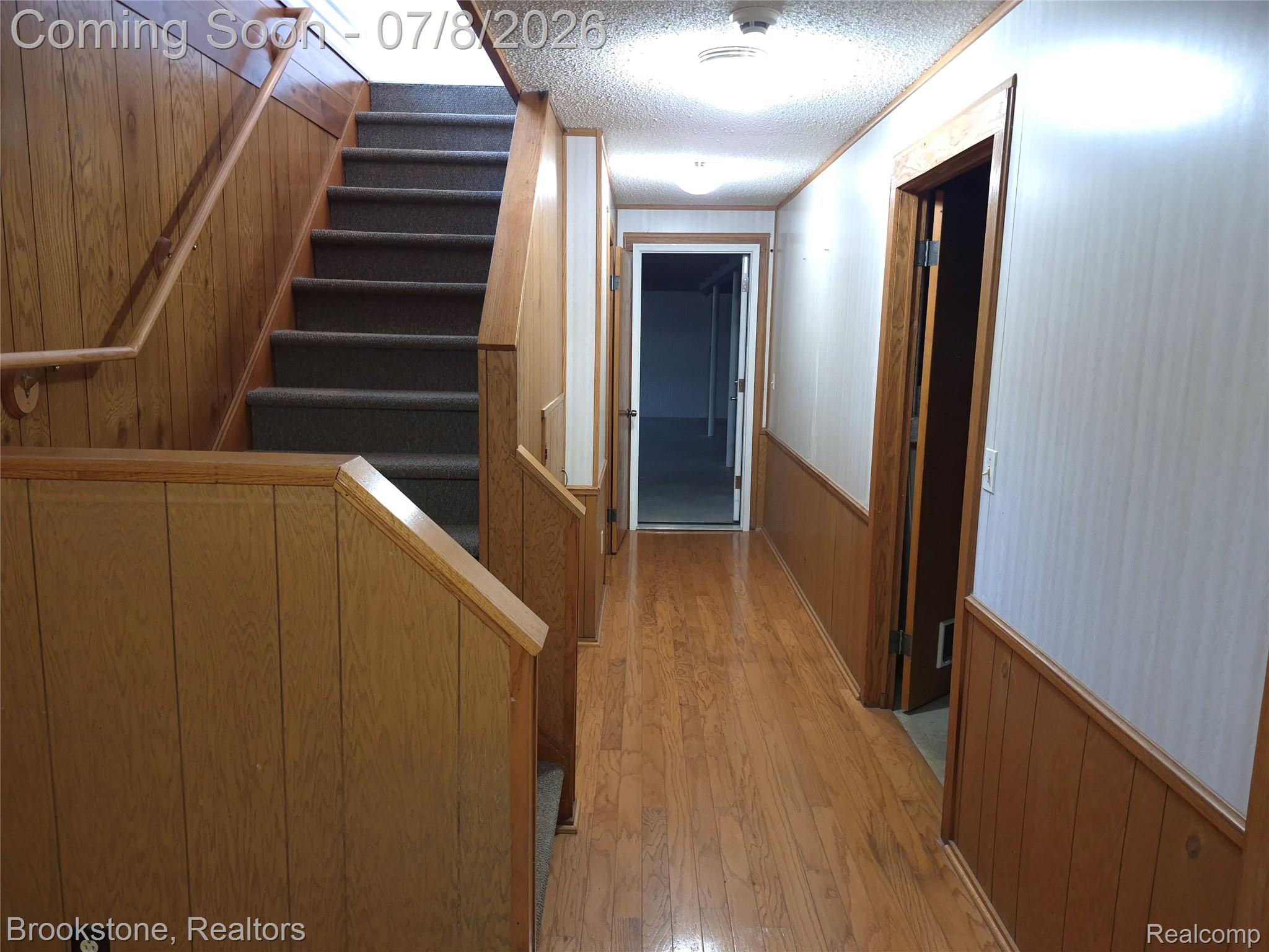 4140 South Henderson Road Davison, MI 48423 - Photo 71 of 98 Hardwood flooring extends through a hallway with wood paneling and light-toned upper walls