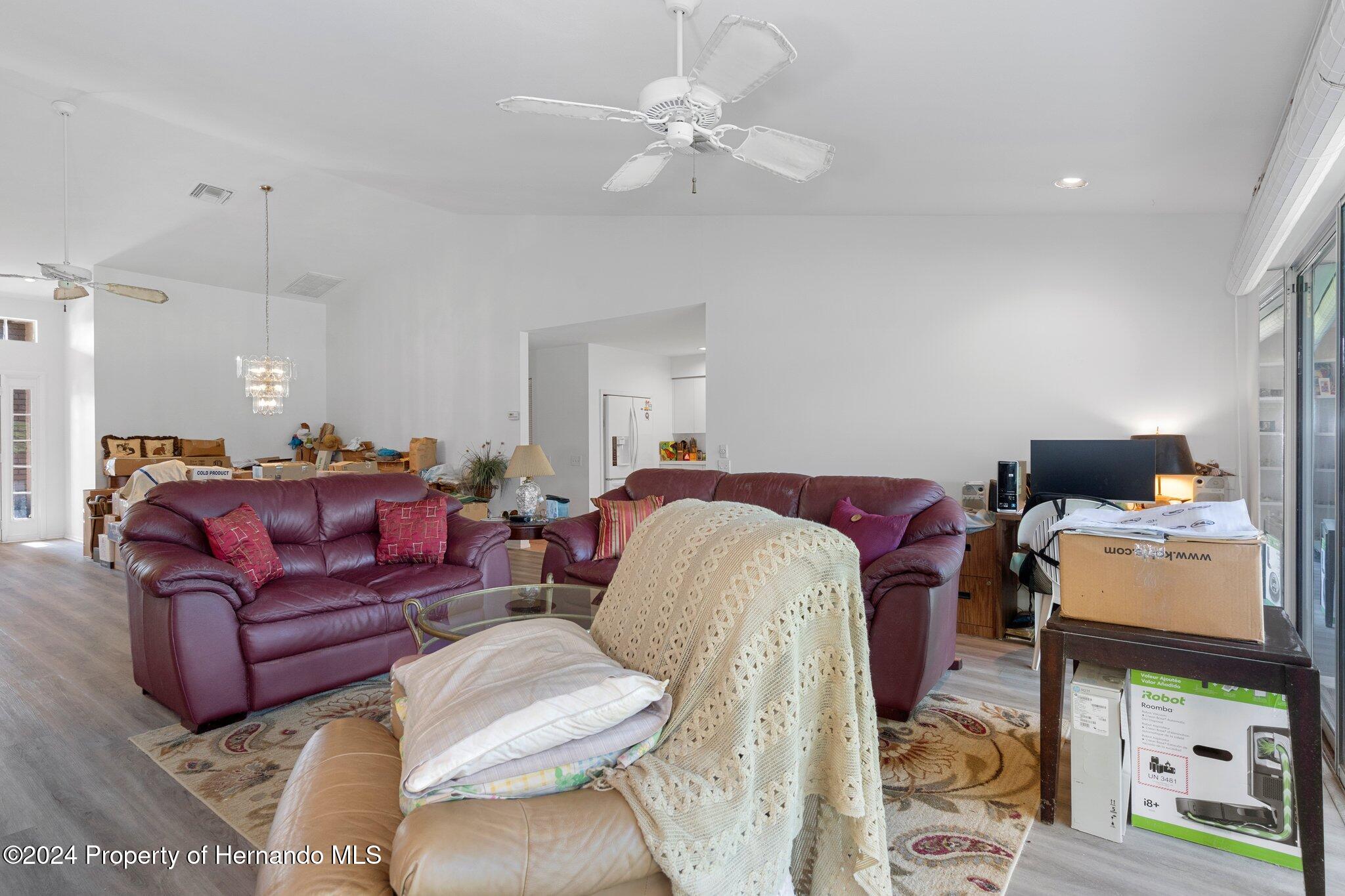 3160 Whispering Pines Court Spring Hill, FL 34606 - Photo 11 of 37 a living room with furniture a couch and a chandelier