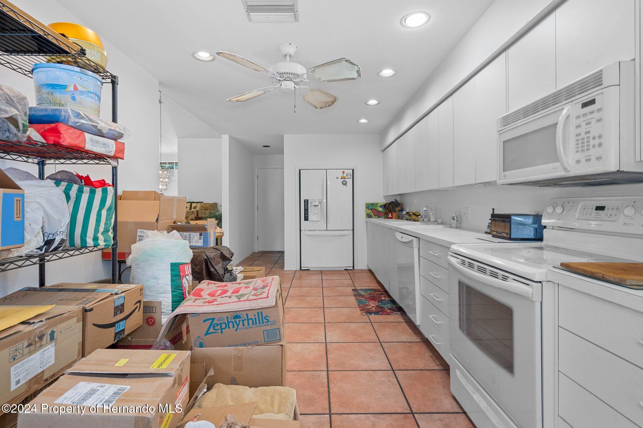 3160 Whispering Pines Court Spring Hill, FL 34606 - Photo 13 of 37 a kitchen with stainless steel appliances granite countertop a sink and dishwasher a stove top oven with white cabinets