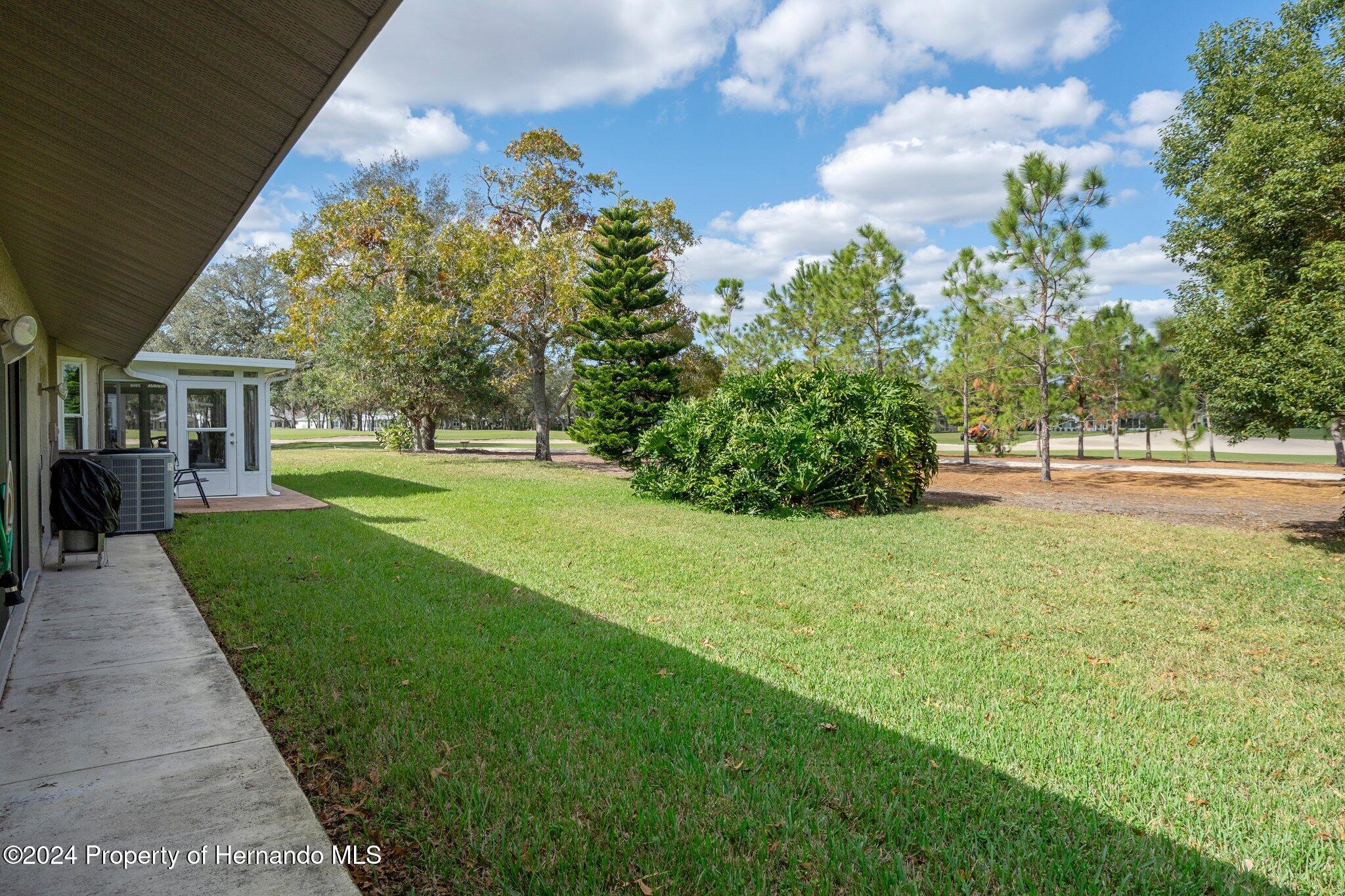 3160 Whispering Pines Court Spring Hill, FL 34606 - Photo 28 of 37 a view of a garden with a building in the background
