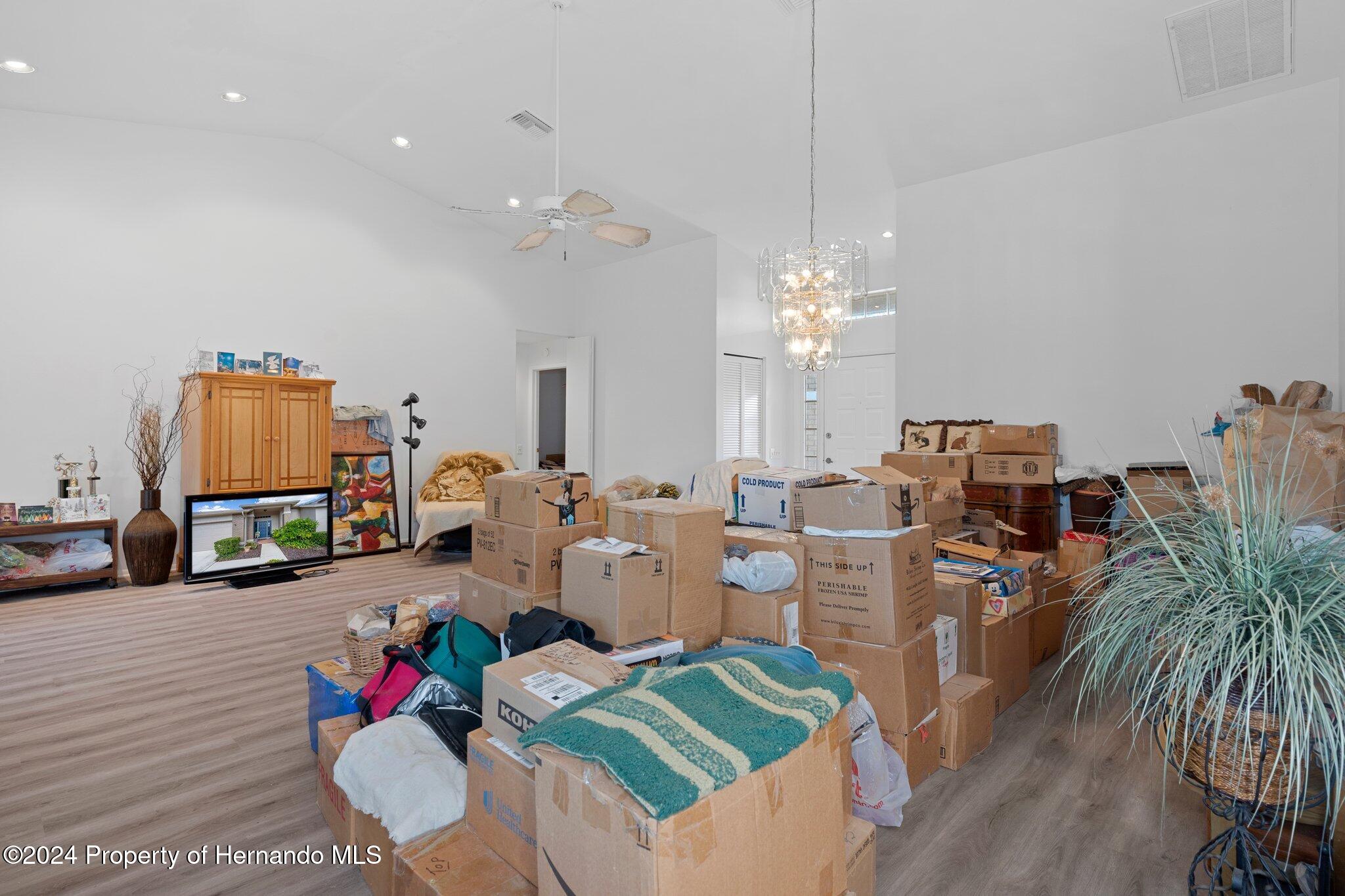 3160 Whispering Pines Court Spring Hill, FL 34606 - Photo 7 of 37 a living room with furniture and a chandelier