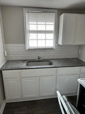 a kitchen with granite countertop white cabinets and a sink