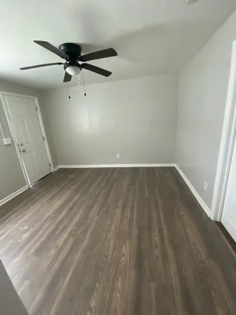 an empty room with wooden floor fan and windows