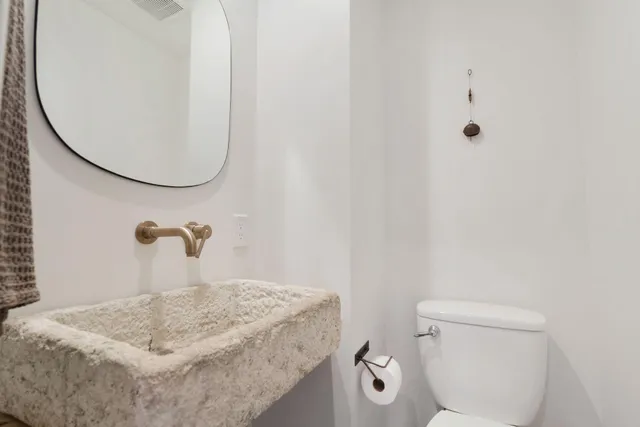 a bathroom with a sink a toilet and a mirror