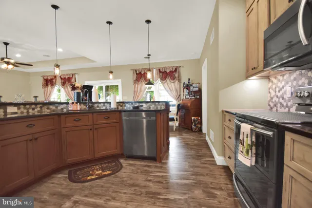 a kitchen with stainless steel appliances granite countertop a sink a stove and a wooden floors