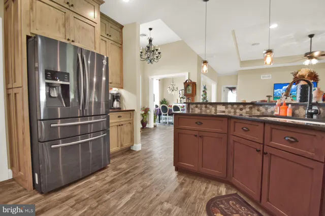 a kitchen with stainless steel appliances granite countertop a refrigerator a oven and a sink with wooden floors