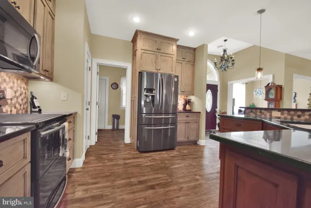 a kitchen with stainless steel appliances granite countertop a refrigerator a sink dishwasher and wooden cabinets with wooden floor