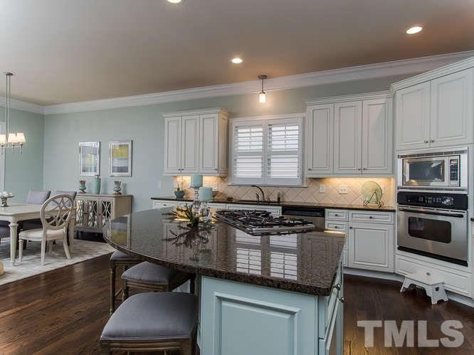 12221 Beestone Lane Raleigh, NC 27614 - Photo 4 of 25 a kitchen with stainless steel appliances granite countertop a stove a sink a microwave a dining table and chairs