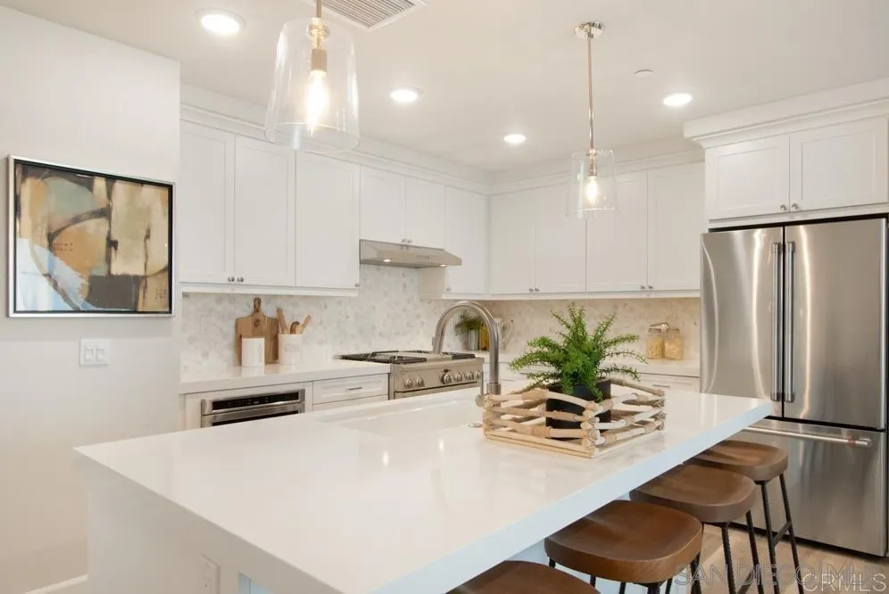 348 Walnut Avenue Carlsbad, CA 92008 - Photo 10 of 20 a kitchen with stainless steel appliances a white refrigerator a sink a stove and white cabinets with wooden floor