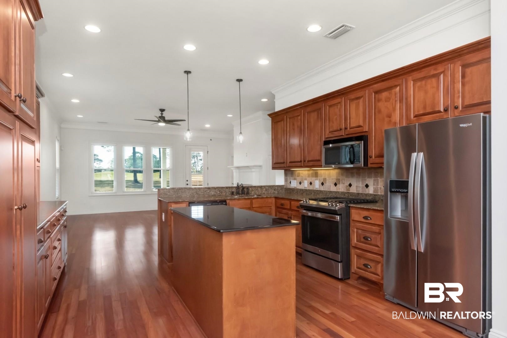 30585 Pine Court Daphne, AL 36527 - Photo 34 of 49 Kitchen with stainless steel appliances, brown cabinets, a peninsula, decorative light fixtures, and crown molding