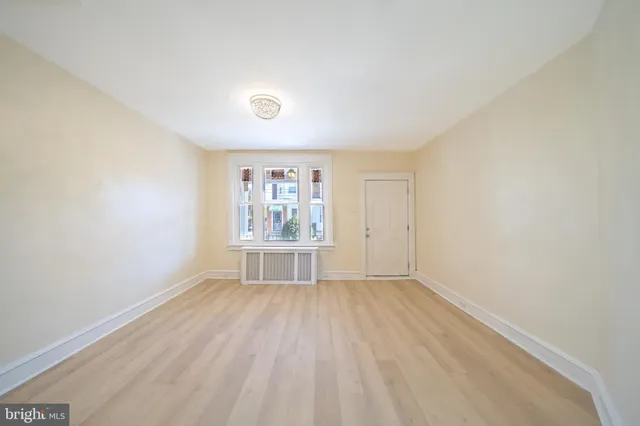an empty room with wooden floor and window