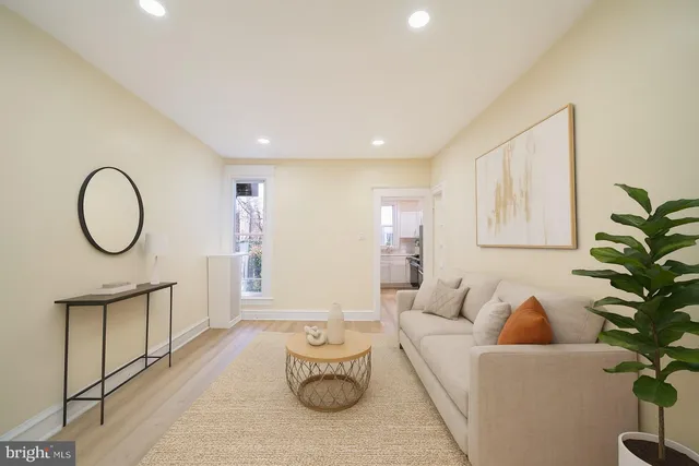 a living room with furniture a potted plant and a large window