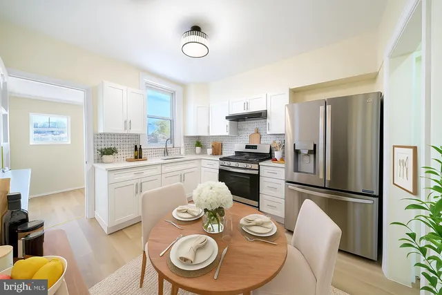 a kitchen with stainless steel appliances granite countertop a refrigerator a stove a microwave and a dining table with wooden floor