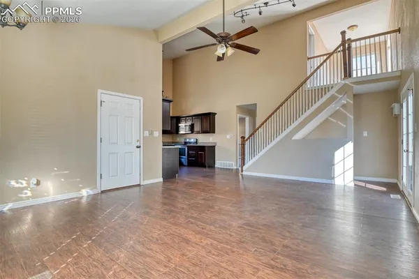 a view of a livingroom with wooden floor and a kitchen space