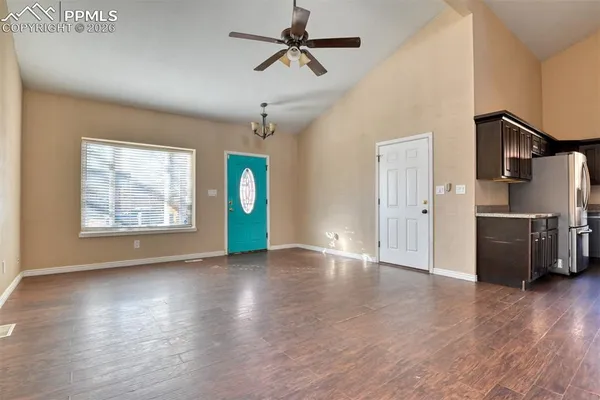 an empty room with wooden floor chandelier and windows