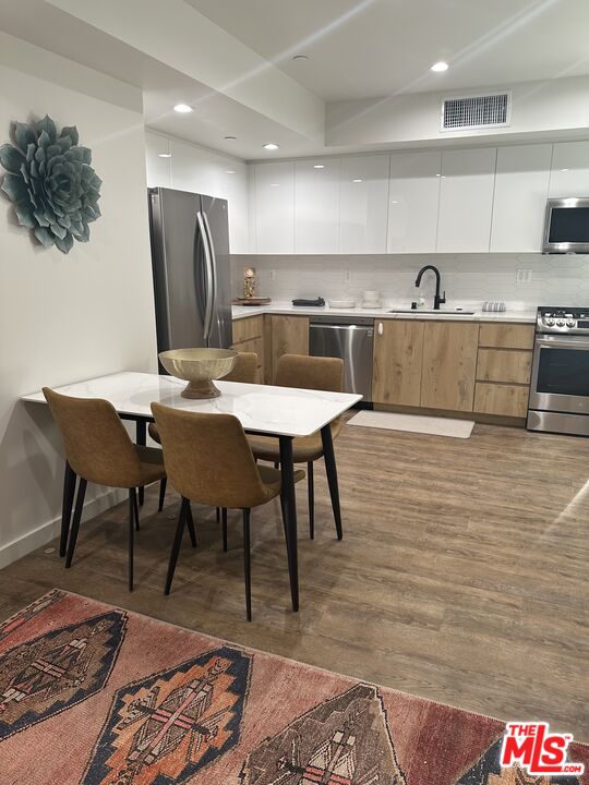 124 South Croft Avenue, Unit 101 Los Angeles, CA 90048 - Photo 21 of 22 a kitchen with stainless steel appliances granite countertop a table chairs sink and cabinets