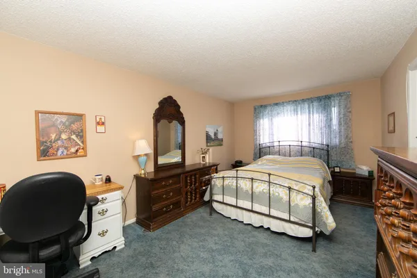 a spacious bedroom with a bed and dresser