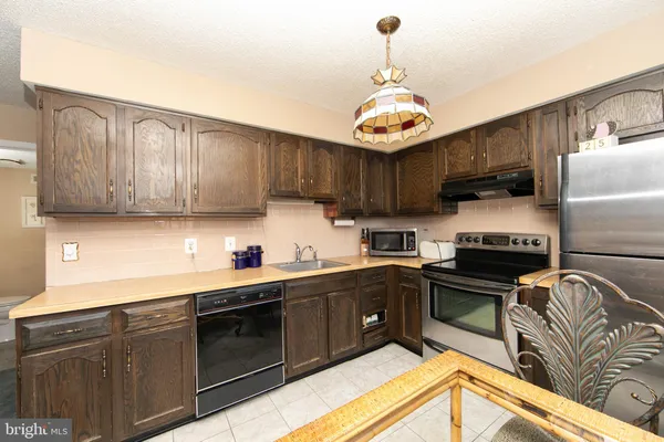 a kitchen with stainless steel appliances wooden cabinets a stove top oven a sink and dishwasher