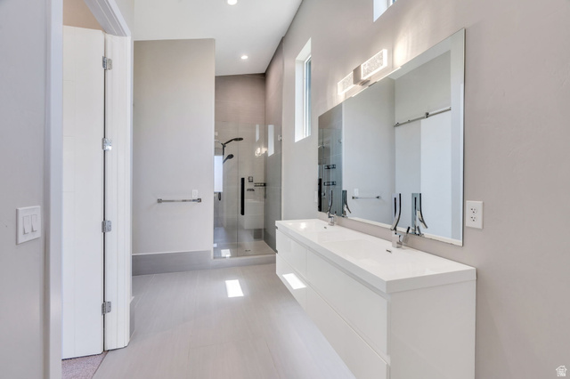 7045 South 300 East Midvale, UT 84047 - Photo 23 of 49 Contemporary bathroom featuring a floating dual vanity with integrated sinks, a glass-enclosed shower, light wood-finish flooring, and two elongated vertical windows