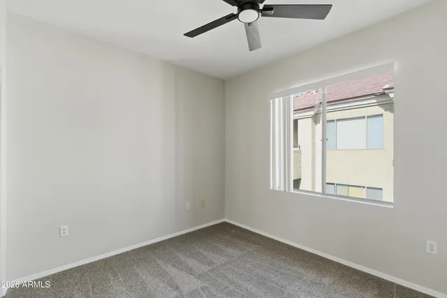 an empty room with a window and a fan
