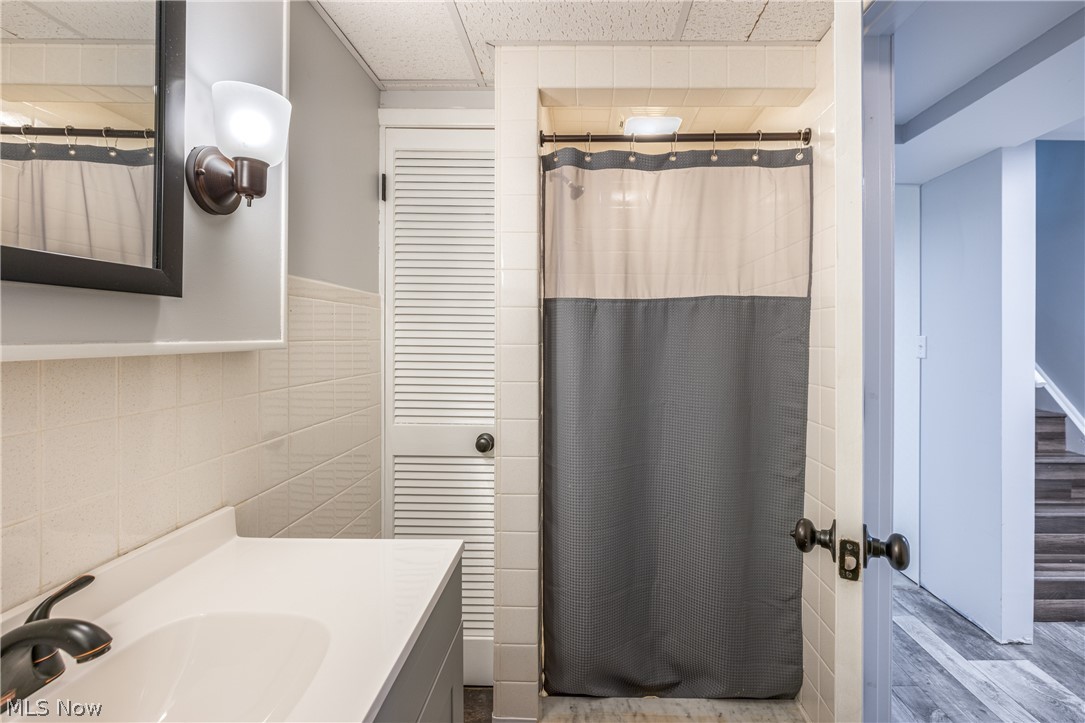 29220 Ridge Road Wickliffe, OH 44092 - Photo 26 of 34 Bathroom featuring wood-type flooring, a paneled ceiling, tile walls, and large vanity