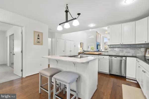 a kitchen with stainless steel appliances granite countertop wooden floors a stove a white table and chairs