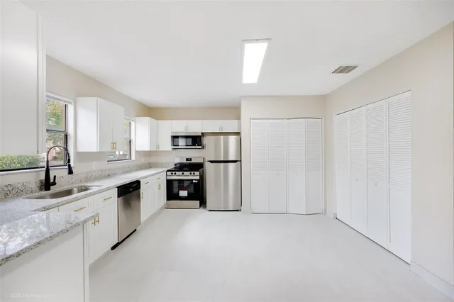 a kitchen with stainless steel appliances granite countertop a refrigerator and a sink
