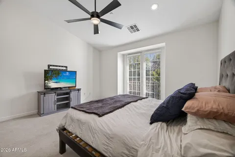 a spacious bedroom with a bed and a flat tv screen