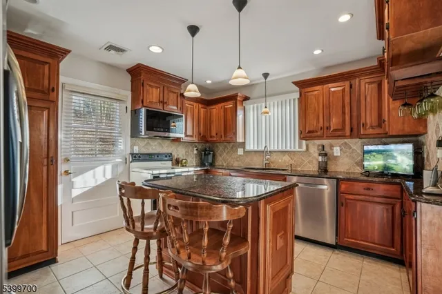 a kitchen with stainless steel appliances granite countertop a sink a stove a refrigerator and a microwave