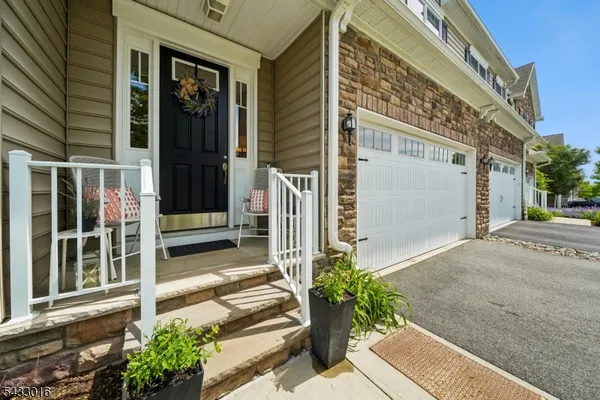 a house with a flower garden and potted plants in front of door
