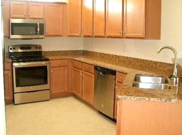 a kitchen with stainless steel appliances granite countertop a stove a microwave and a sink