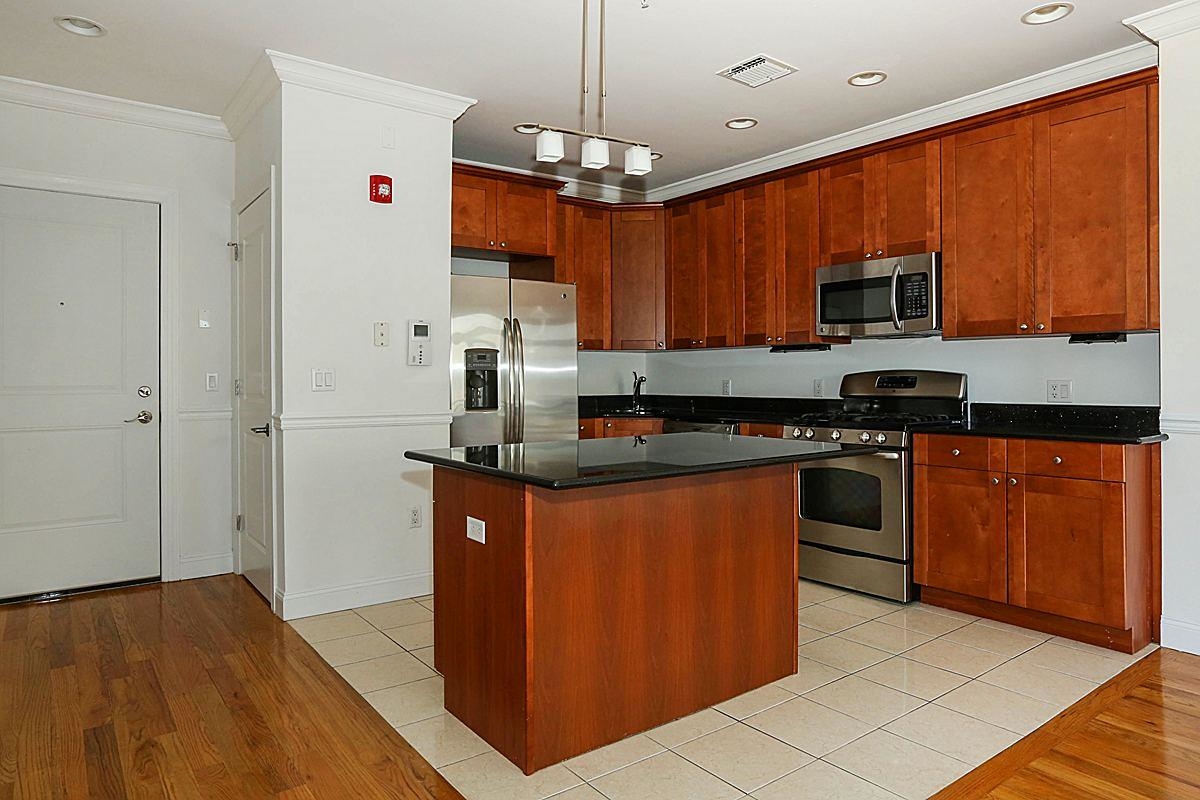 a kitchen with stainless steel appliances granite countertop a stove top oven a sink dishwasher and a refrigerator with wooden cabinets