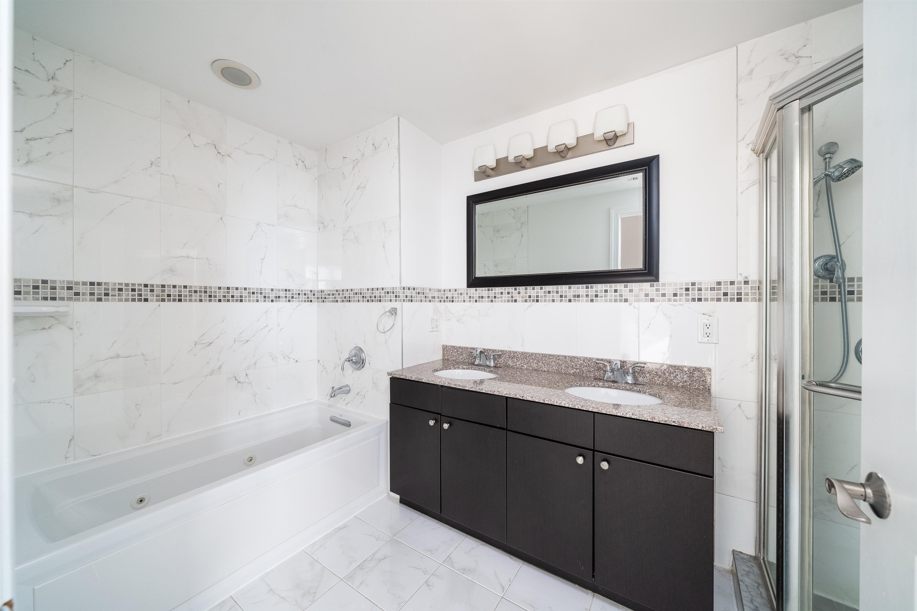 85 Maple Street, Unit 2A Weehawken, NJ 07086 - Photo 5 of 11 a bathroom with a bathtub shower sink vanity and mirror