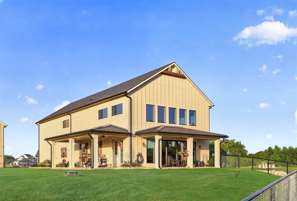 985 Vest Lane Pilot Point, TX 76258 - Photo 4 of 40 Two-story residential structure featuring vertical siding, a dark shingle roof, and a prominent gable
