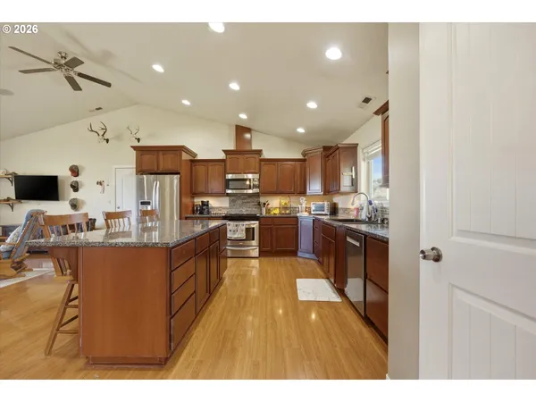a kitchen with stainless steel appliances kitchen island granite countertop a refrigerator and a sink